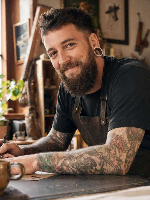 Mann mit Bart und Tattoos trägt große echte Flesh Tunnel