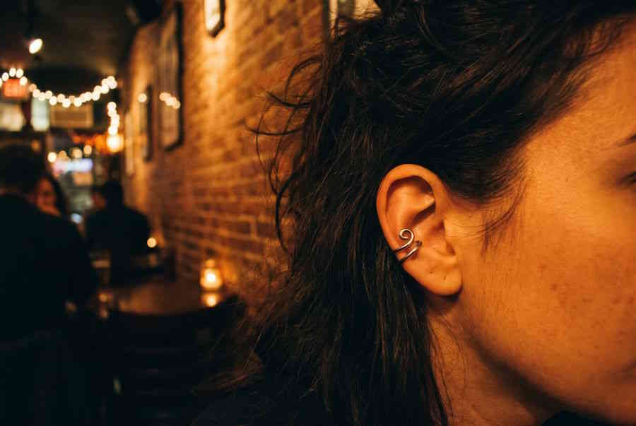 Fake Helix Piercing – Frau mit silbernem Ear Cuff am Ohrknorpel