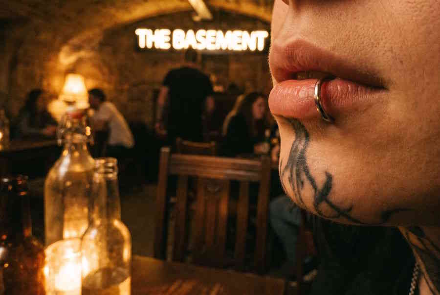 Fake Lippenpiercing – Mann mit Tattoos und Fake Lip Ring in Bar-Atmosphäre