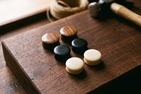Geschlossene Ohr Plugs aus braunem Holz, schwarzem Horn und hellem Knochen auf Holzuntergrund